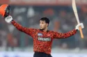 Abhishek Sharma of Sunrisers Hyderabad celebrates scoring 141 runs in IPL 2025, holding his bat high in a floodlit stadium with fireworks in the sky and a cheering crowd in the background.