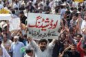 “A crowd of people protesting in Lahore under the scorching sun with signs and police presence, during a severe heatwave and power outage.”