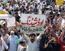 “A crowd of people protesting in Lahore under the scorching sun with signs and police presence, during a severe heatwave and power outage.”