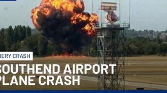 Wreckage of small medical plane crash in flames at London Southend Airport with smoke billowing into the sky, emergency responders on scene.