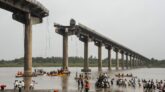 Collapsed portion of the Gambhira Bridge with rescue teams retrieving vehicles from Mahisagar River in Vadodara, Gujarat.